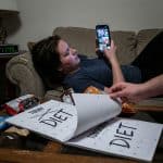 한 손으로 스마트폰을 들고 짧은 영상을 계속 넘기며, 다른 손으로는 다이어트라고 적힌 달력 페이지를 내일